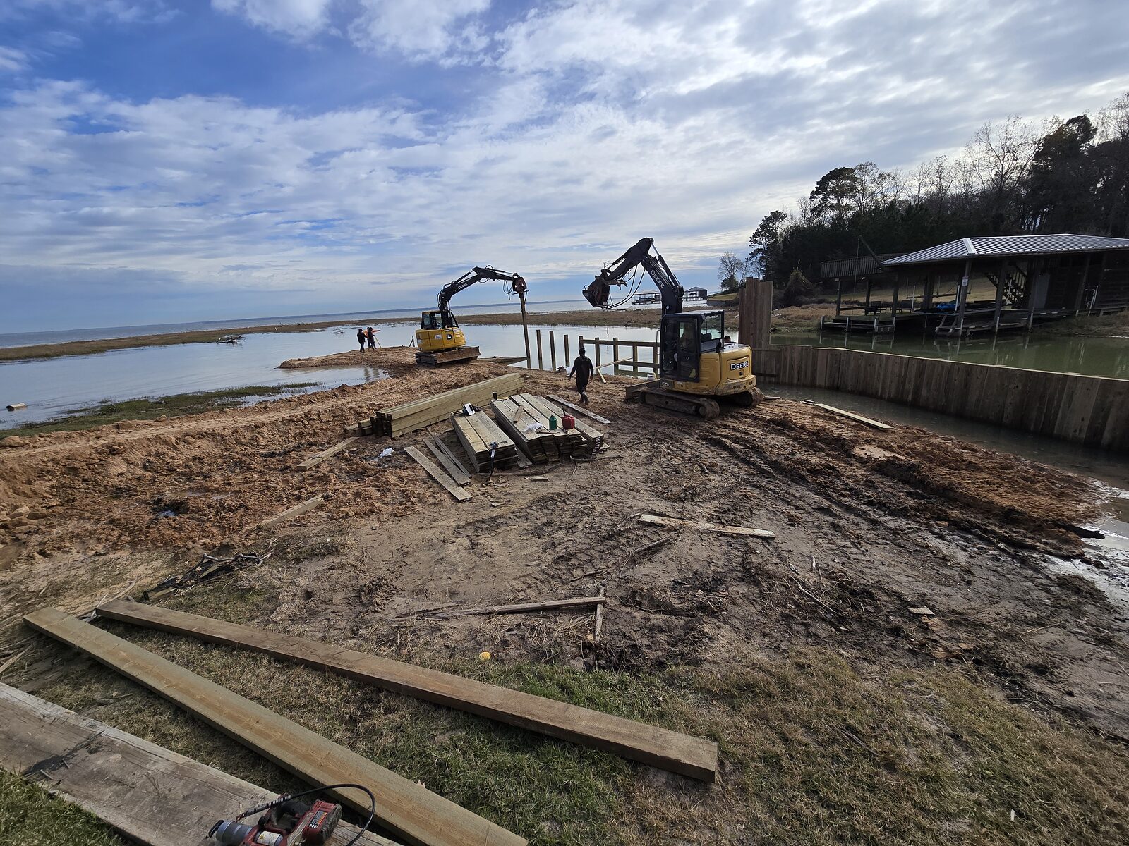 Shore Tech excavator setting a new shoreline bulkhead along calm open lake water in East Texas