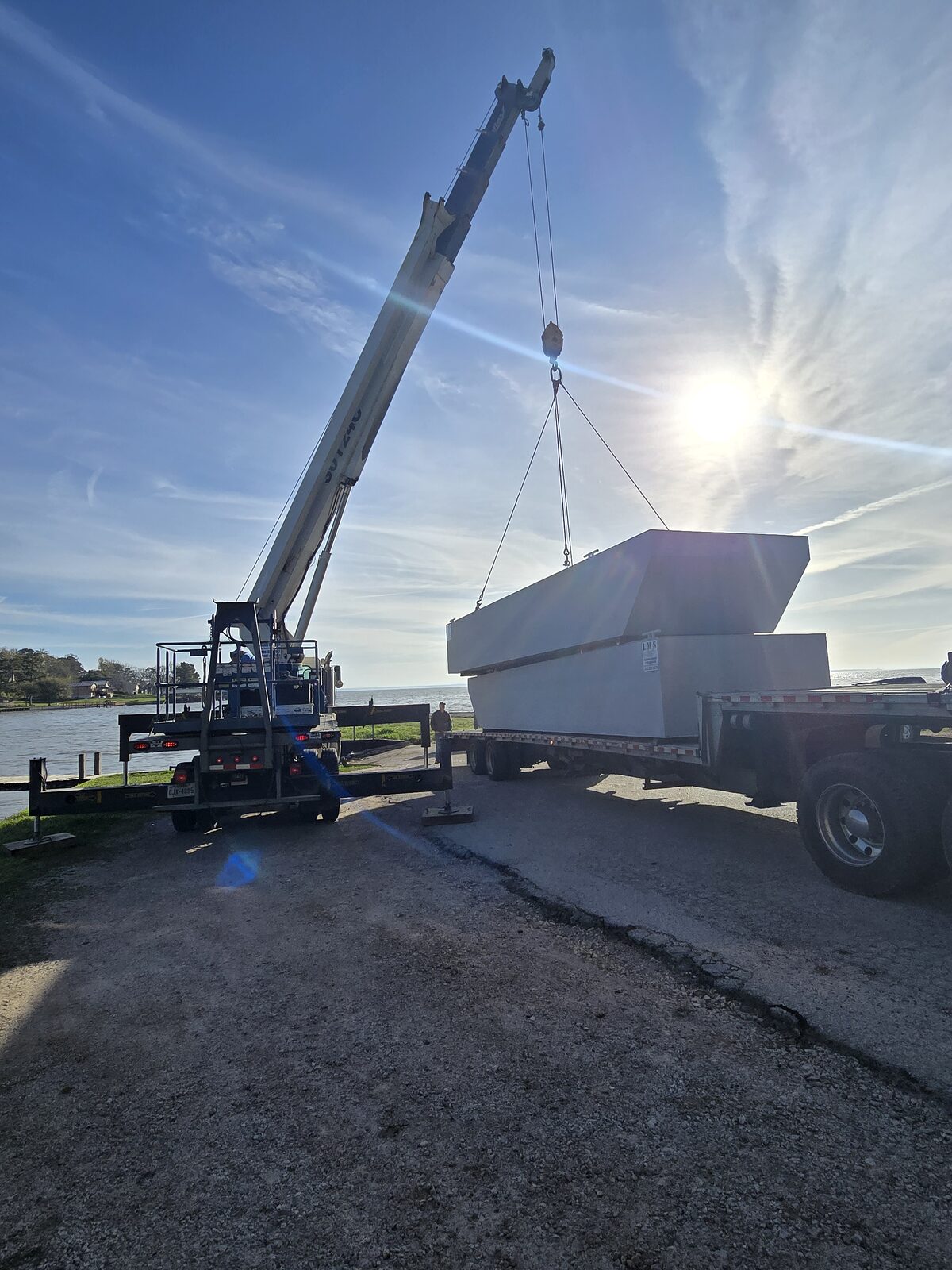 Marine crane lifting a fabricated module onto a barge for a commercial waterfront project