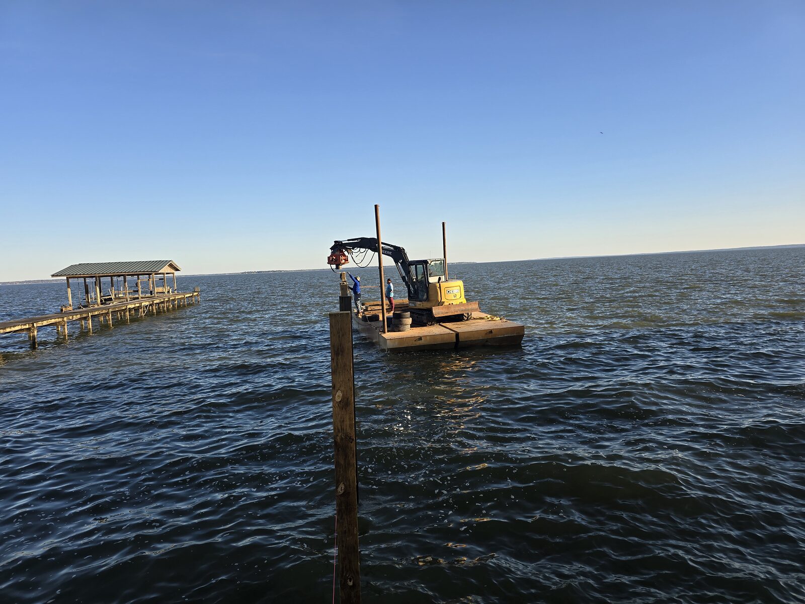Shore Tech barge driving the outboard piles that carry a boathouse roof and deck loads at dusk